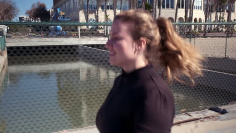 Enthusiastic-fit-woman-jogging-on-the-sandy-pathway-of-Santa-Monica-beach-residence-California