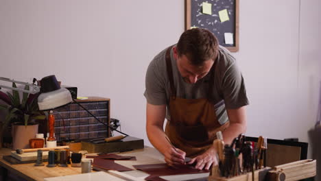 Man-with-apron-marks-detail-outlines-on-leather-in-workshop