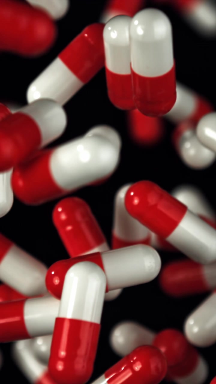 Capsule di medicinali rosse e bianche che cadono al rallentatore
