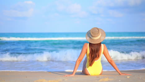 Mujer-Sentada-En-La-Playa-De-Arena-Blanca-Frente-Al-Mar