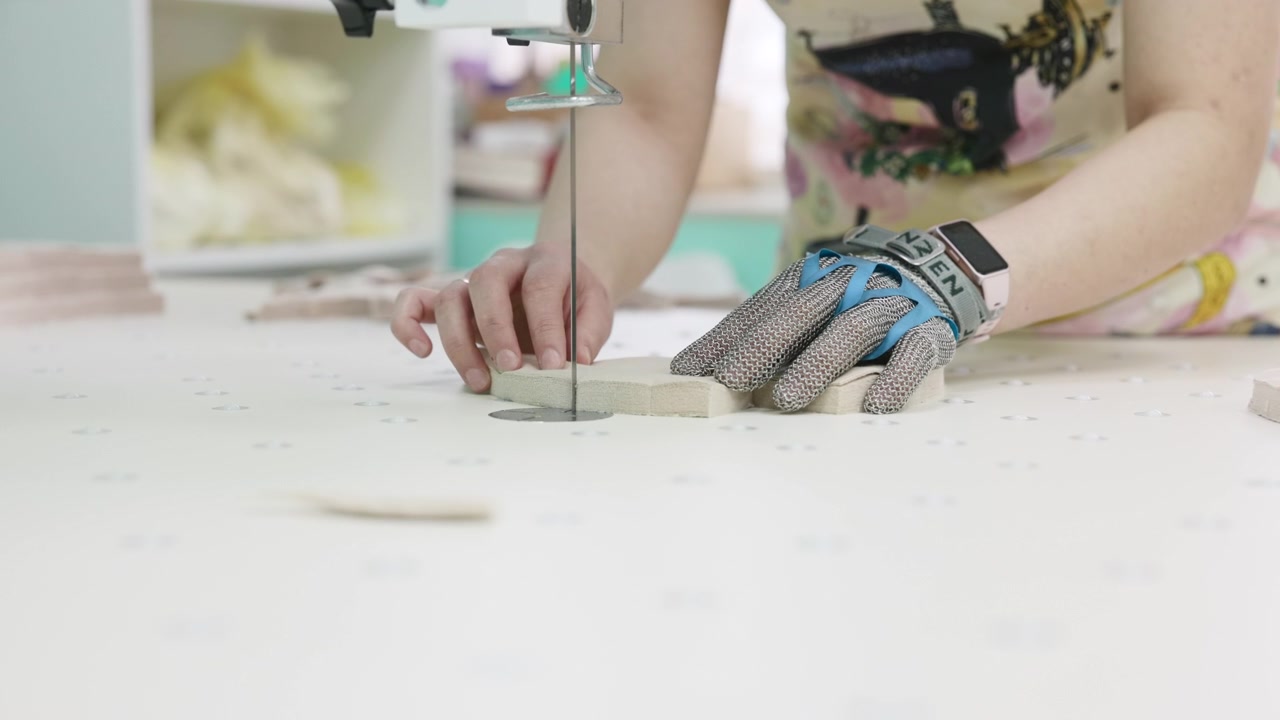 Closeup Gloved Hands Cutting Shape On Tabletop Saw, Steady Feed And Blade Travel Cutting Small Parts . Media