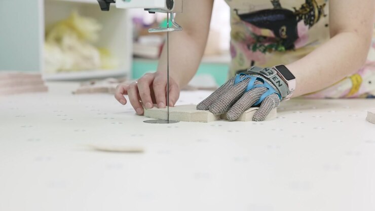 Closeup Gloved Hands Cutting Shape On Tabletop Saw, Steady Feed And Blade Travel Cutting Small Parts . Media