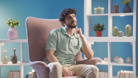 Stressed-young-man-sitting-alone-on-sofa,-lost-in-his-thoughts.