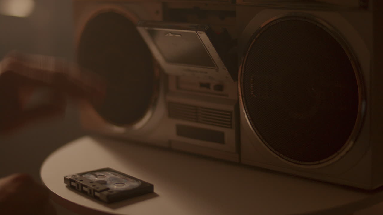 Hand Inserting Compact Cassette into Boombox, then Turning On Music