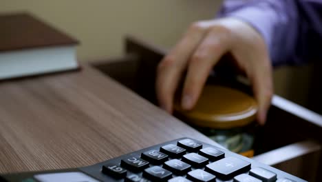 Caucasian male putting a glass jar put in a drawer  table with his savings for future retirement