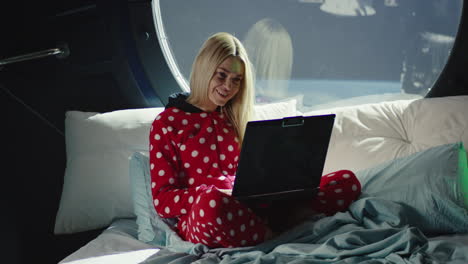 Woman working on a laptop in space pajamas