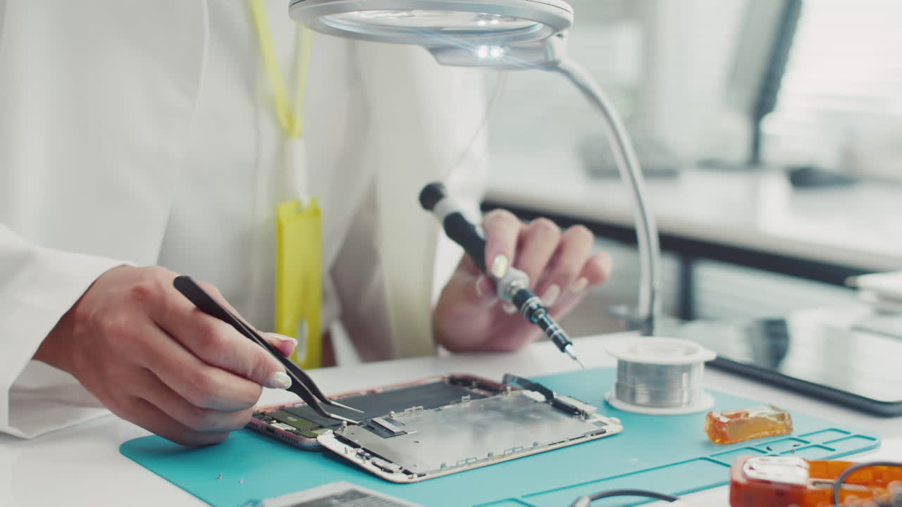 Technician Using Tweezers when Examining Phone Broken Detail