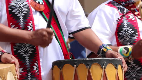 native american drummers in traditional dress playing drums at a pow wow in the american southwest