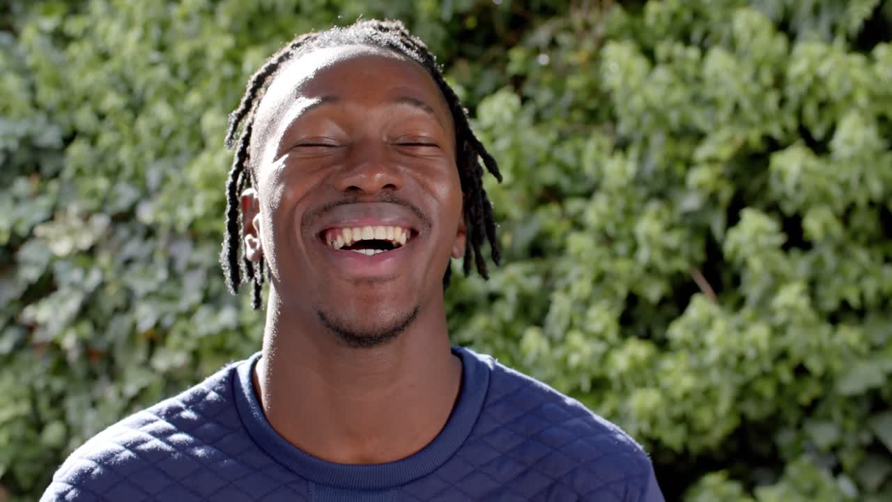 Retrato de hombre afroamericano feliz en jardín soleado, a cámara lenta.