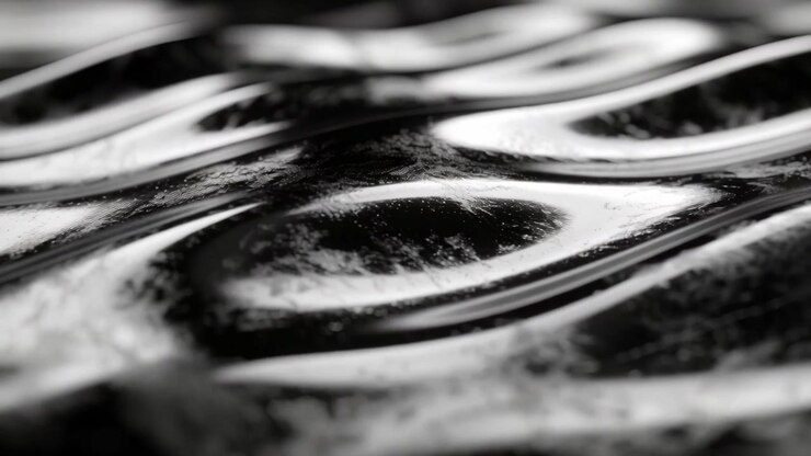 Shifting camera forward revealing glossy rippled surface changing in studio light highlighting form