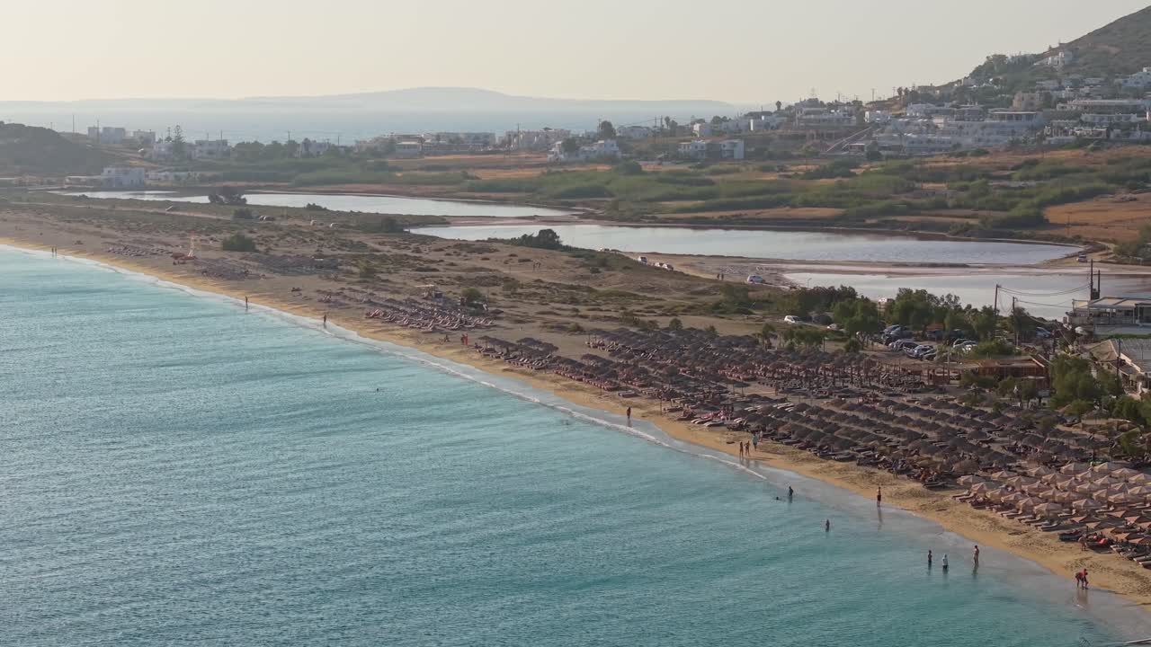 Aerial view of Agios Prokopios Beach in Naxos, showcasing its expansive golden shoreline lined with vibrant beach bars and crystal-clear waters