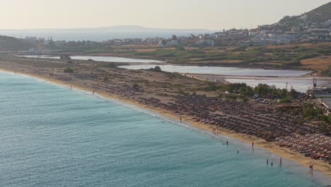 aerial view of agios prokopios beach in naxos, showcasing its expansive golden shoreline lined with vibrant beach bars and crystal-clear waters