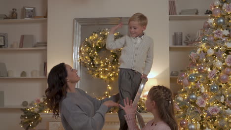 Madre-Choca-Los-Cinco-Con-Un-Niño-Y-Una-Niña-Después-De-Decorar-El-árbol-De-Navidad