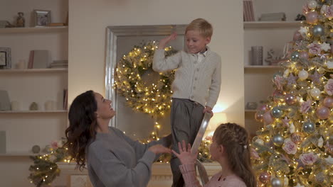 madre choca los cinco con un niño y una niña después de decorar el árbol de navidad