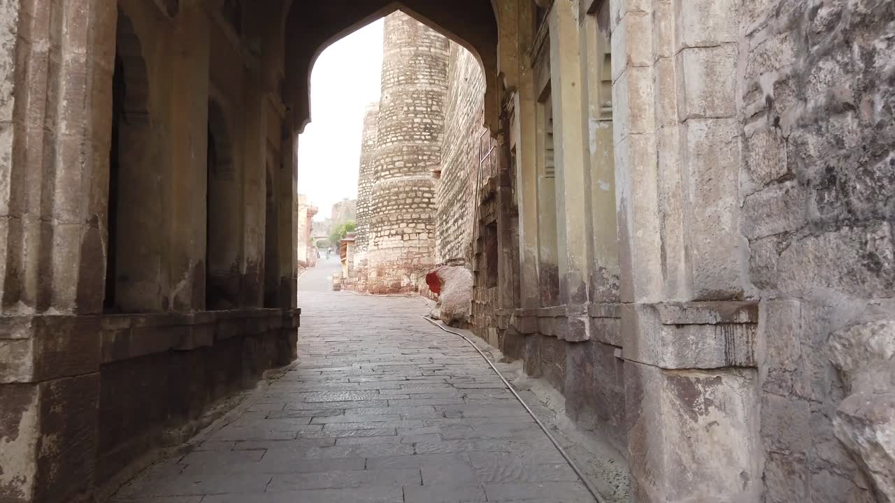 tiro de seguimiento caminando a través del arco principal del fuerte de mehranarh en jodhpur, rajasthan, india