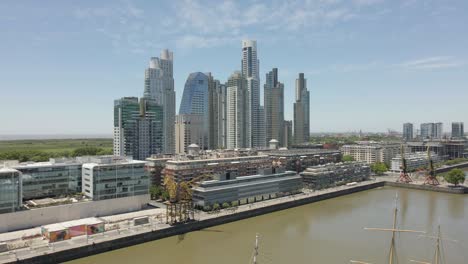 Vista-Aérea-Del-Paseo-Marítimo-De-Puerto-Madero-En-Buenos-Aires,-Argentina-En-Un-Día-Soleado-Con-El-Horizonte-De-La-Ciudad-Al-Fondo---Disparo-De-Drones