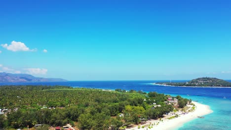 Paradise-tropical-island-gateway-with-quiet-exotic-beach-around-green-trees-washed-by-calm-clear-water-of-blue-turquoise-sea-on-a-bright-blue-sky-background