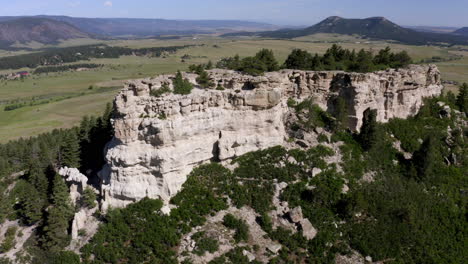 aerial views of a grassy plane heading to a beautiful rock formation in palmer lake colorado