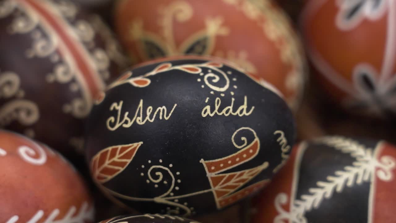 Close-up of a single black Easter egg with handwritten Hungarian folk text and decorations