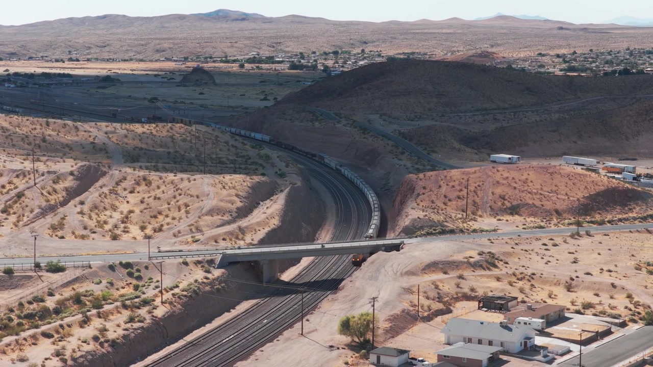 Ripresa aerea ravvicinata in discesa di un treno merci in movimento che attraversa il deserto a Barstow, California. 4K.