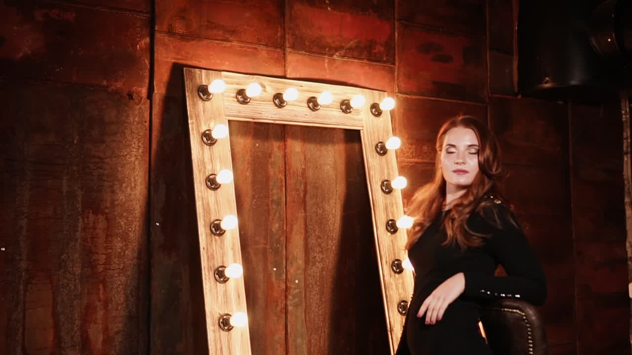 검은 드레스 를 입은 여자 가 빈티지 거울 앞 에 포즈 를 취 하고 있다