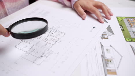 architect at the construction site checks house plan documents with a pencil to check structural design, correctness, and construction strength