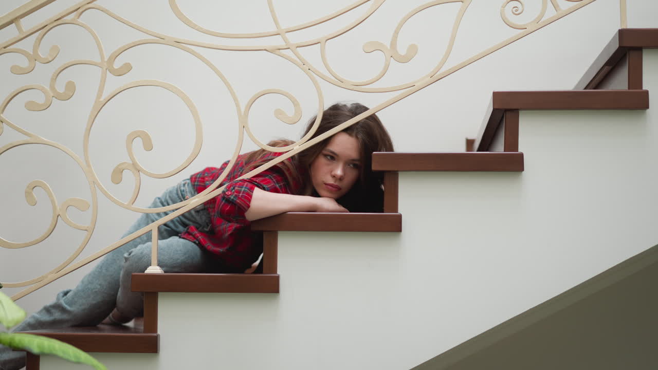 mujer con estado de ánimo depresivo yace en las escaleras. señora agotada pierde la voluntad de hacer tareas de rutina en causa de agotamiento emocional en el hogar. expresión de mujer pensativa