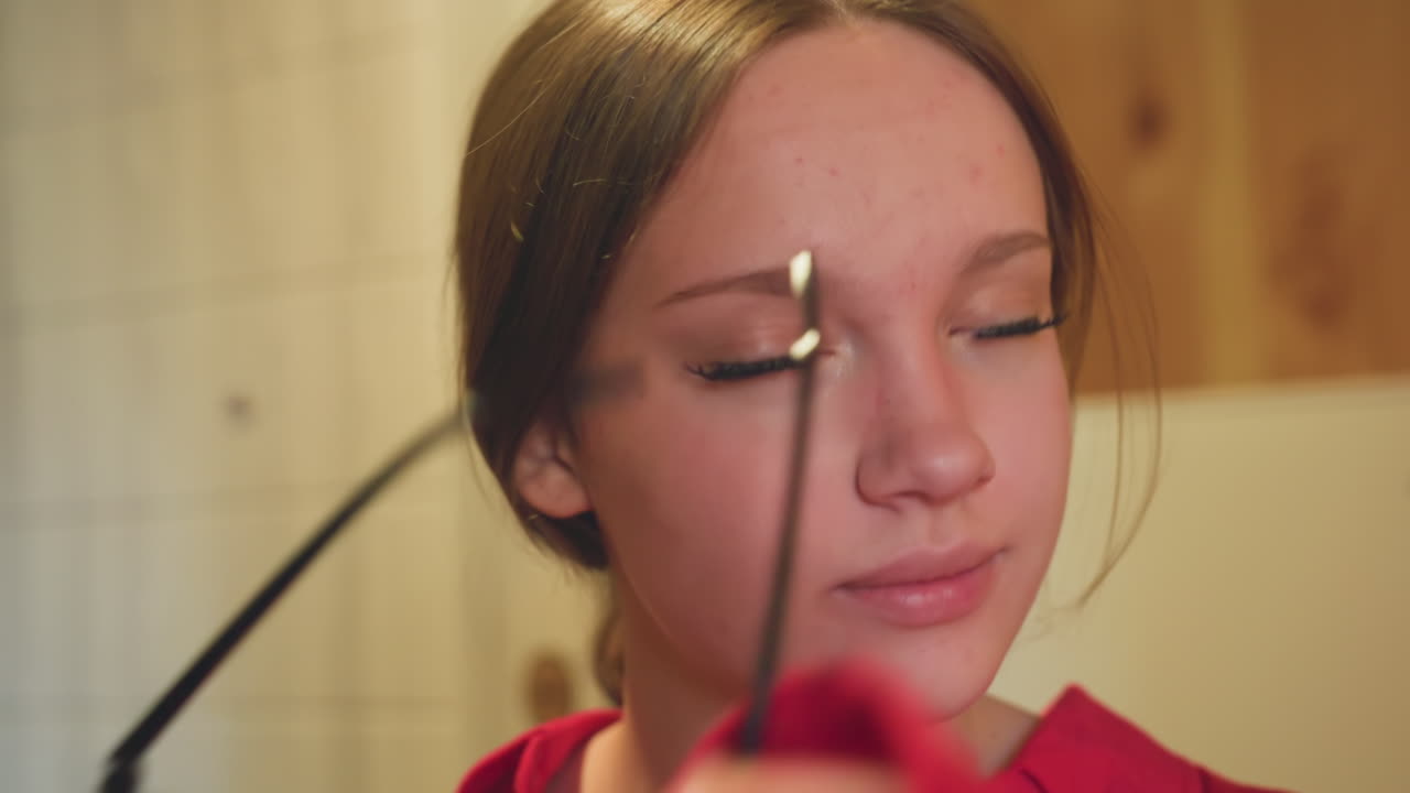 Close up of young woman in red top gently removing sunglasses indoors with slight smile, relaxed expression, and soft lighting in casual interior setting featuring wood and tiled background