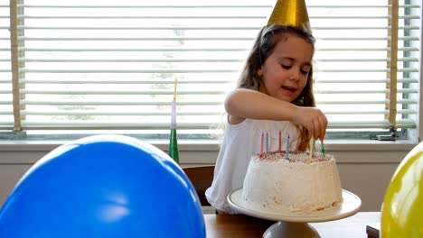 Niña-Colocando-Velas-Sobre-El-Pastel-De-Cumpleaños