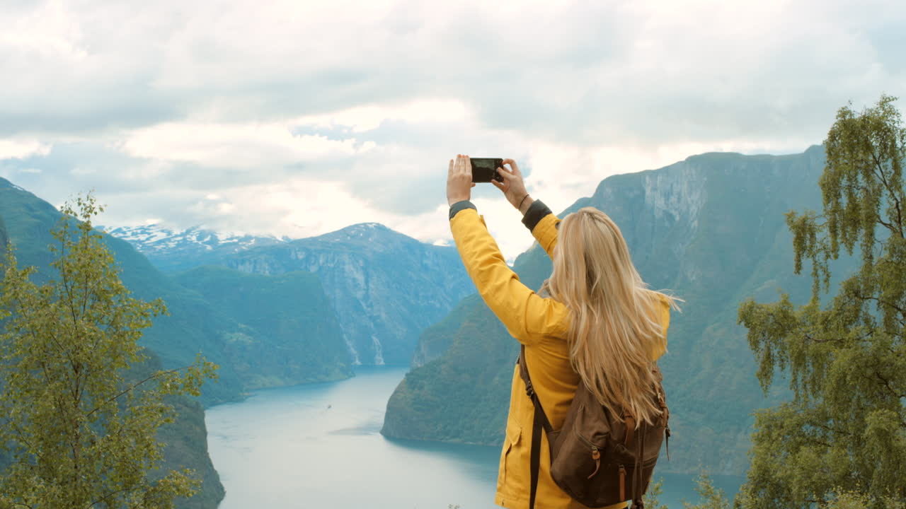 mujer tomando una foto del fiordo noruego