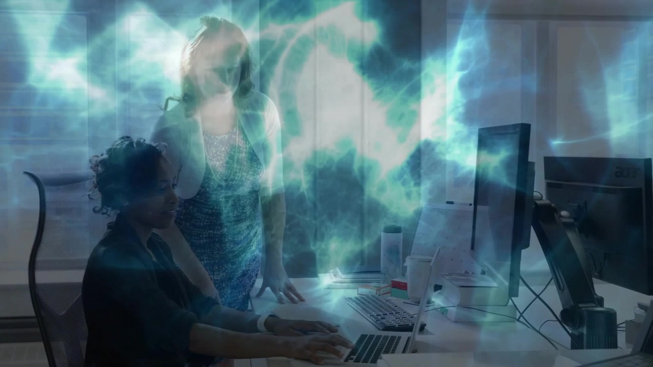 Two women typing on keyboard activating cyan teal nebula overlay showing tech data for analysis