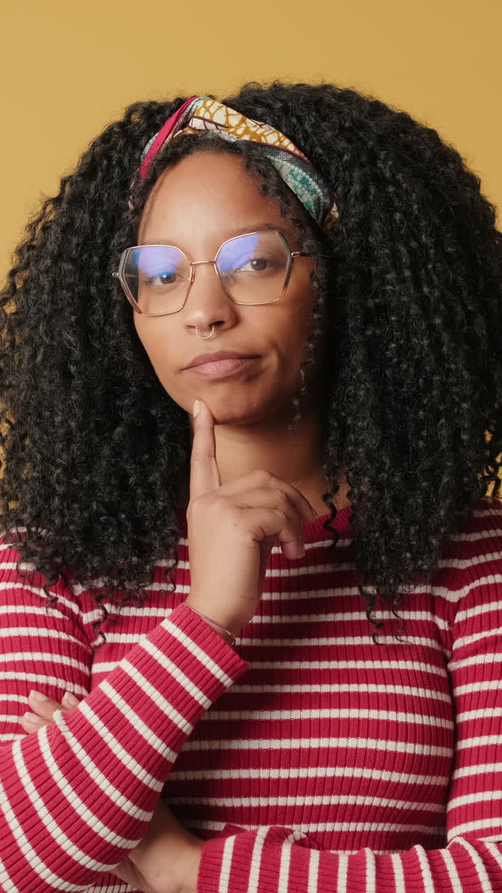 Young Woman with Curly Hair and Glasses Thinking and Smiling