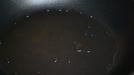 hot soy based oil gets swung around in a black frying pan in order to cover the whole surface with it