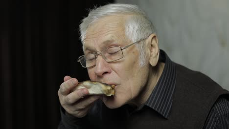 Beautiful-elderly-man-in-glasses-eats-pizza.-Shows-how-tasty-the-pizza-is.