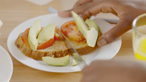 a person cutting avocado and tomato toast