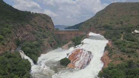 fly toward hartbeespoort dam wall, powerful white water flows down spillway