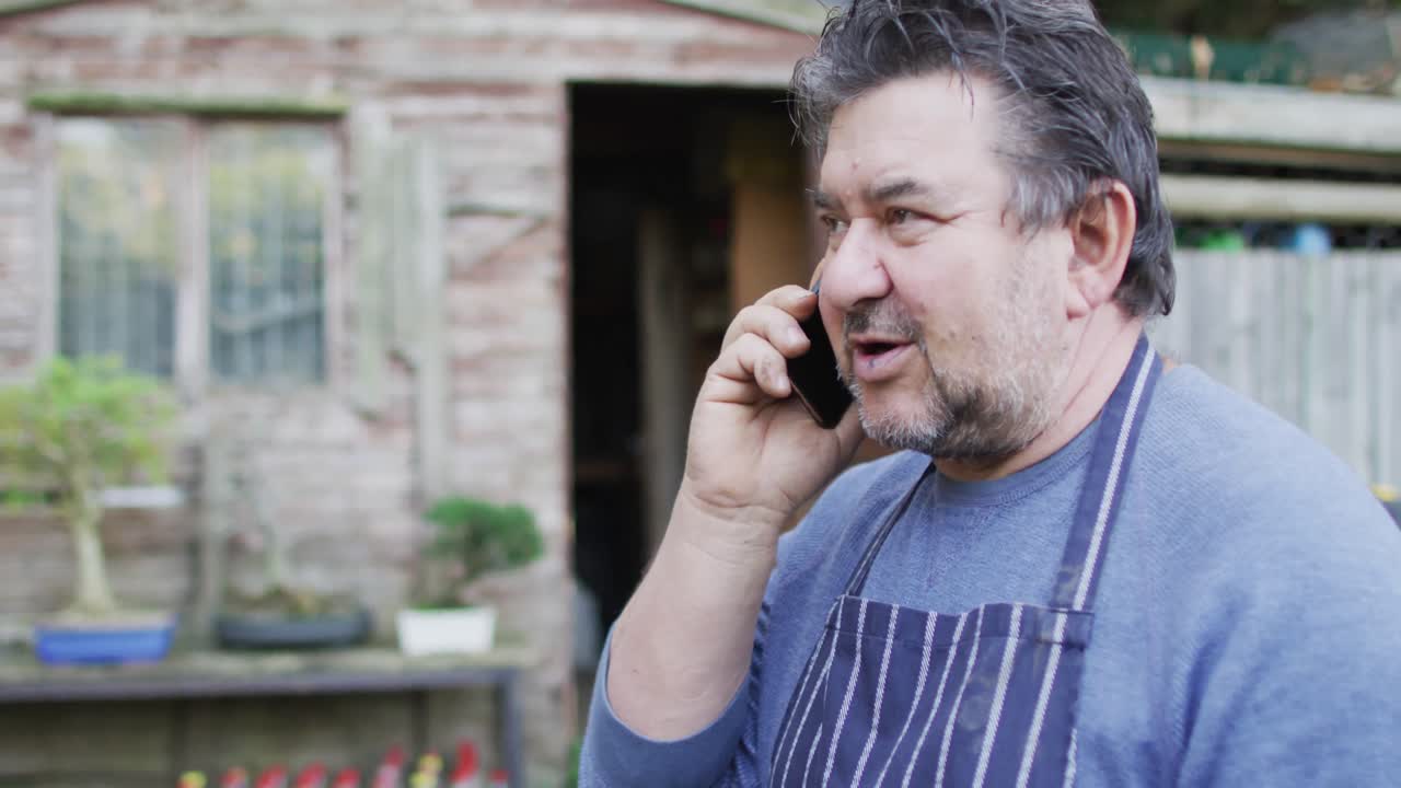 정원 센터에서 스마트폰을 사용하는 백인 남성 정원사