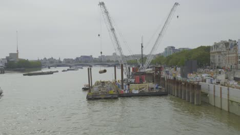 Ein-Blick-Auf-Eine-Baustelle-An-Der-Themse,-Wo-Der-Arbeiter-Pfähle-Auf-Den-Lastkahn-Lädt