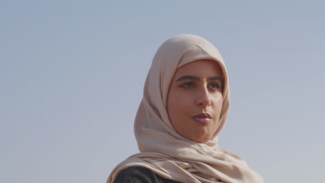 portrait of a muslim woman in hijab dancing and moving her hands smoothly in a windy desert