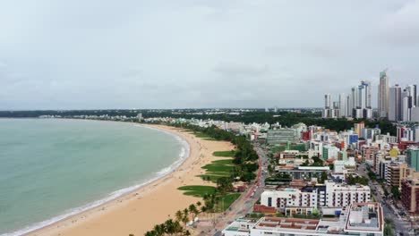 right panning dolly out aerial drone shot of the cityscape of the colorful tropical beach capital city of joao pessoa in paraiba, brazil from the tambaú neighborhood on an overcast morning