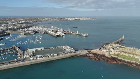 st. peter port guernsey vuelo hacia la terminal de transbordadores con transbordador en el muelle, sobre la bahía de havelett, el rompeolas del castillo y los puertos con vistas a la bahía de belle greve en un día soleado con mar claro y cielo azul