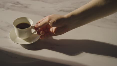 studio shot of person drinking traditional british cup of black tea from cup and saucer