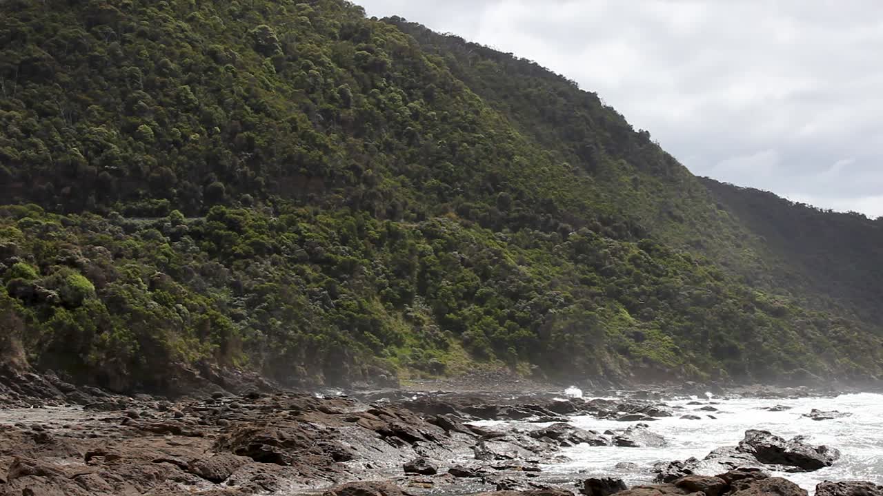 Paesaggio di spiaggia rocciosa impervia con onde bianche che si infrangono sulla costa