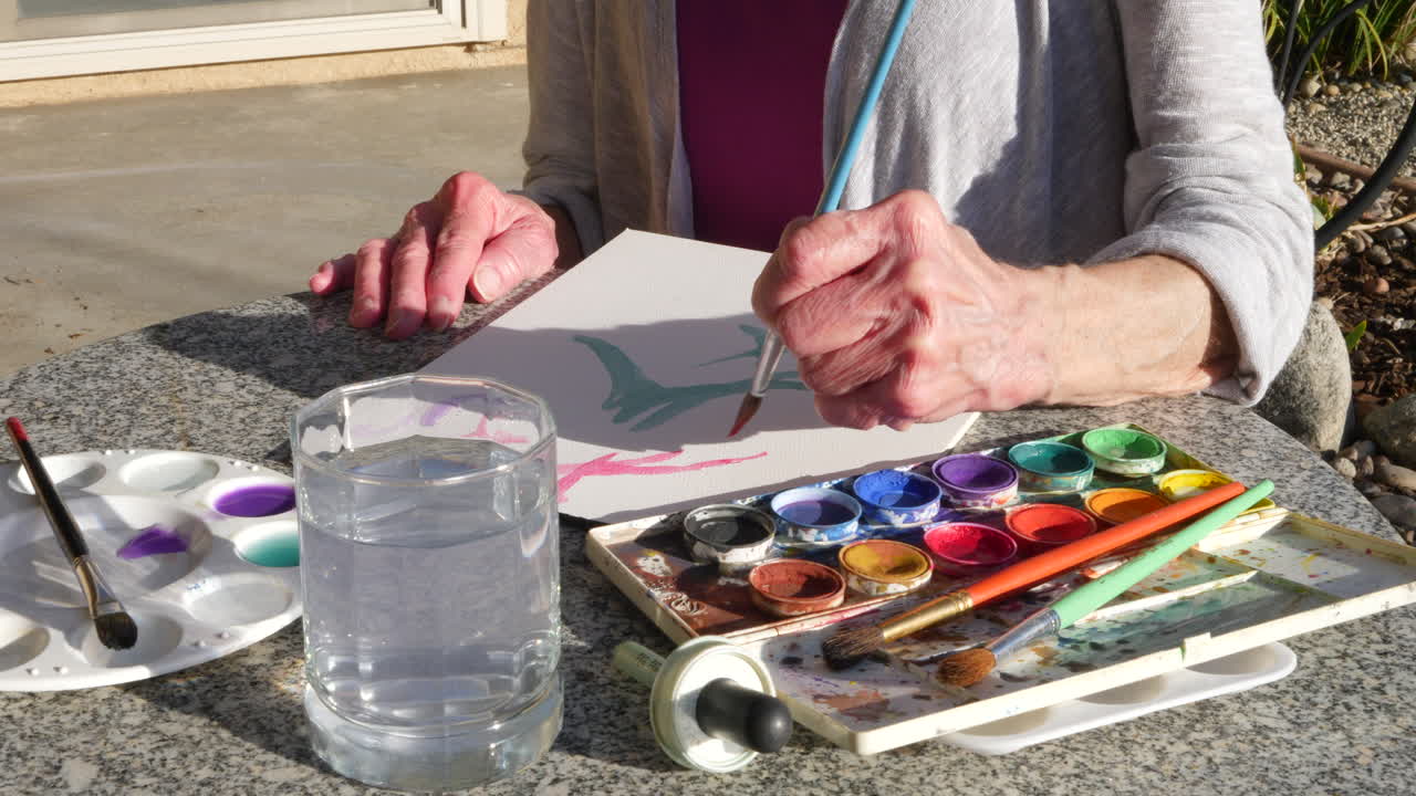 una anciana artista pintando con acuarelas para aliviar el estrés y relajarse en un estudio de arte al aire libre