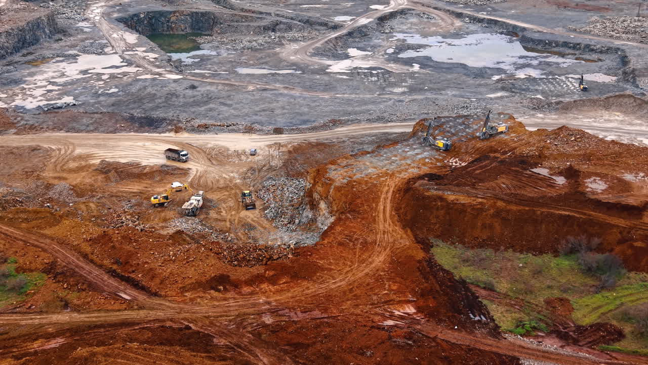 Rock digging by water site. Workers use heavy machines to dig and move soil and rocks at a construction site close to a water area
