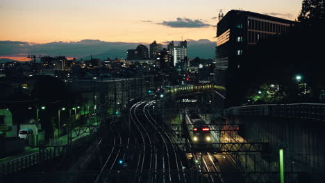 Dos-Trenes-Que-Viajan-En-La-Vía-Férrea-Al-Atardecer-En-La-Ciudad-De-Tokio,-Japón