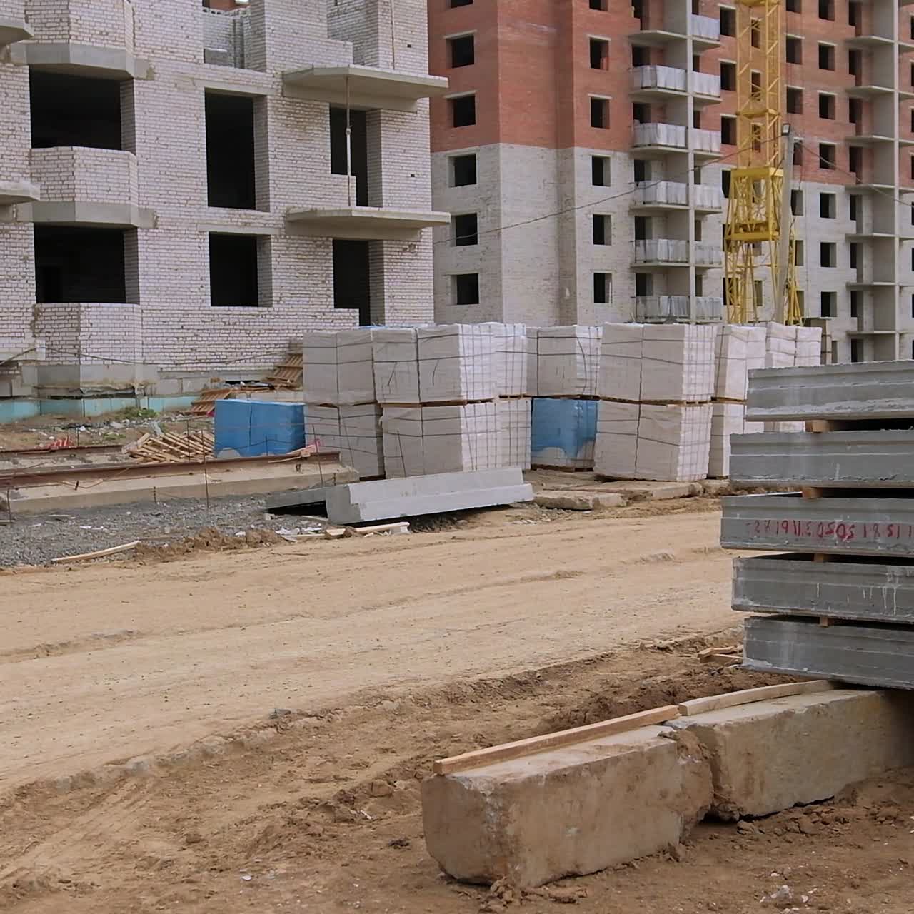 Multistoried blocks of flats construction. Building site with materials prepared for work. Pile of concrete blocks at foreground
