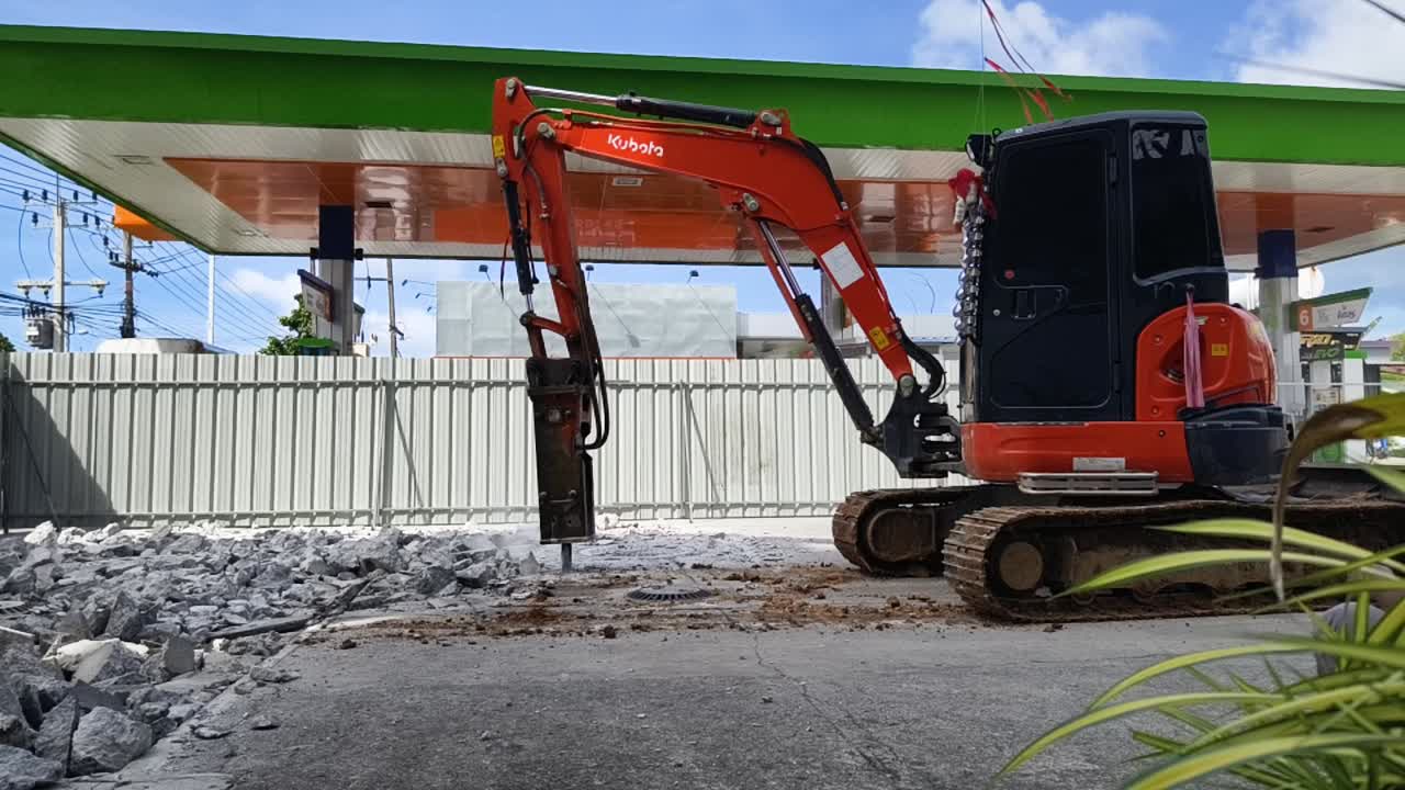 mini excavadora con martillo eléctrico para demoler el hormigón en la gasolinera