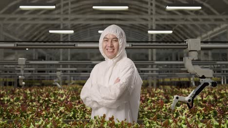 side view of asian man researcher smiling and crossing his arms while standing in the greenhouse with smart robotic farmers