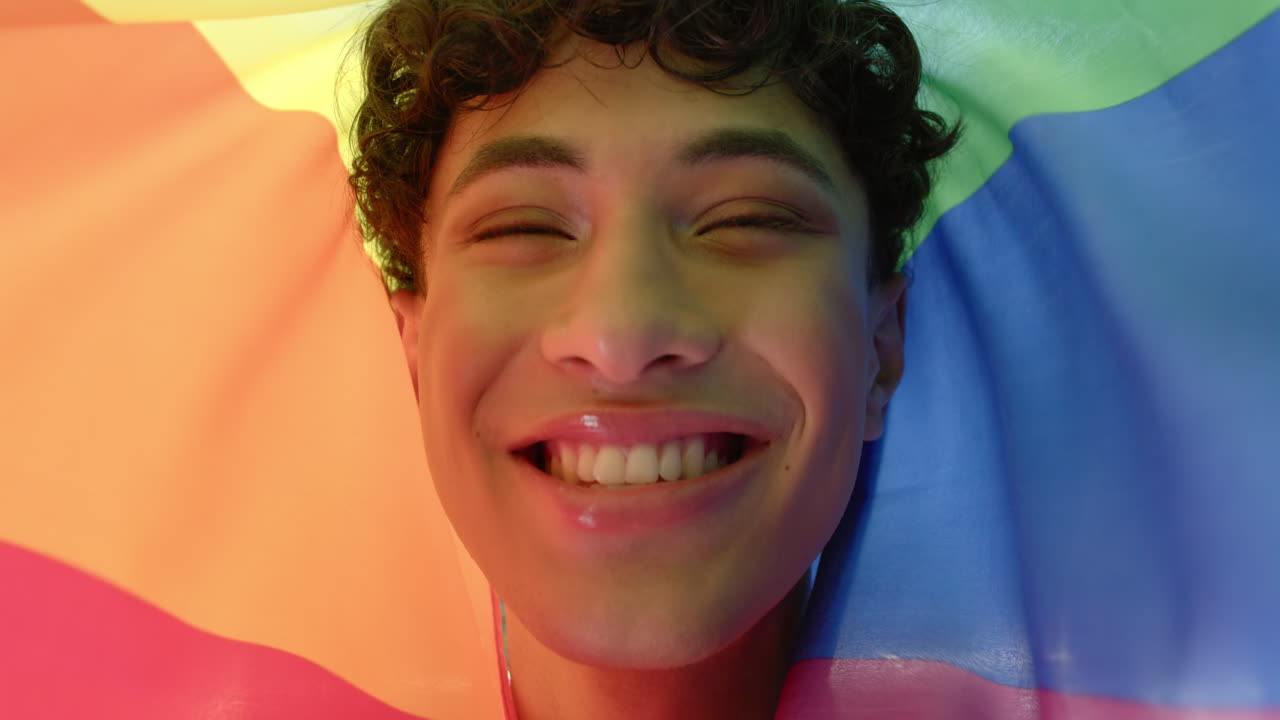 Smiling person wrapped in rainbow flag, celebrating LGBTQ+ pride and diversity